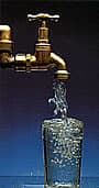 A brass tap filling a glass with water